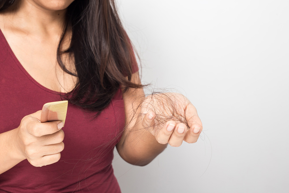 causes-of-hair-loss-woman-with-hairbrush-and-hair.jpg